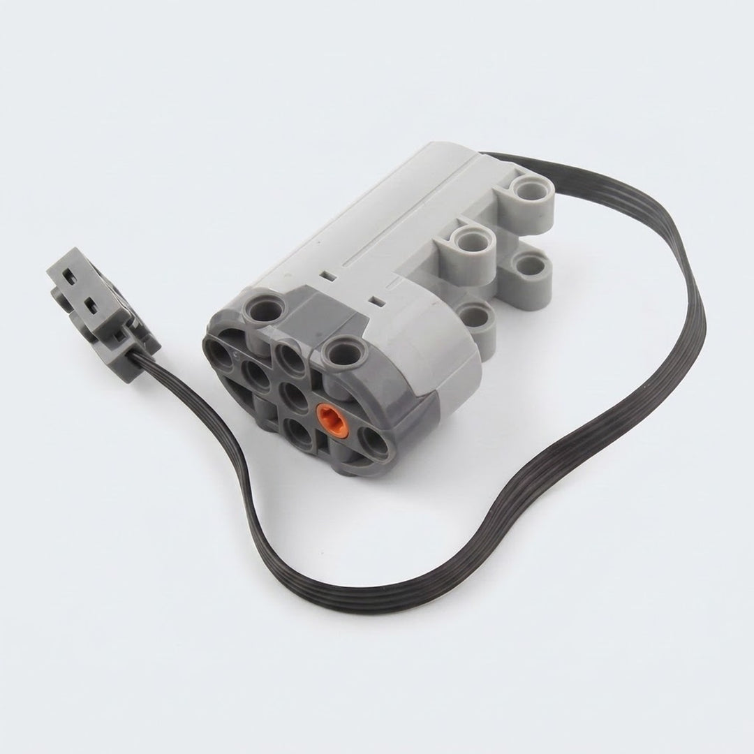 A gray building block servo motor component with mounting holes, an orange axle socket, and a looped black cable rests against white.