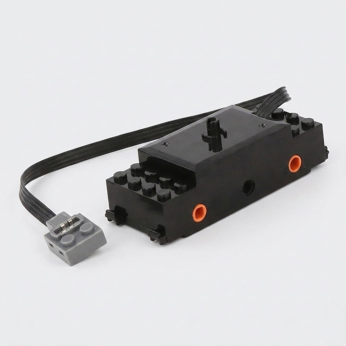 A black building block train motor component with orange axle sockets, a black cable, and a gray connector rests against a white background.