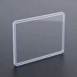 A transparent hard card sleeve with rounded corners stands upright on a dark gray surface.