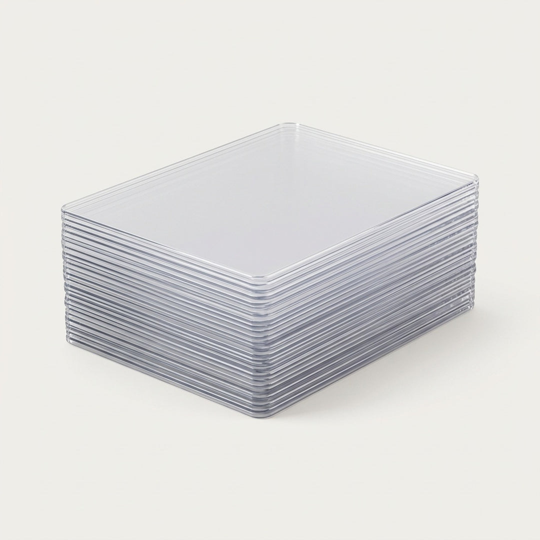 Clear plastic card sleeves are stacked neatly on a plain off-white background, showing their rigid edges and rounded corners.