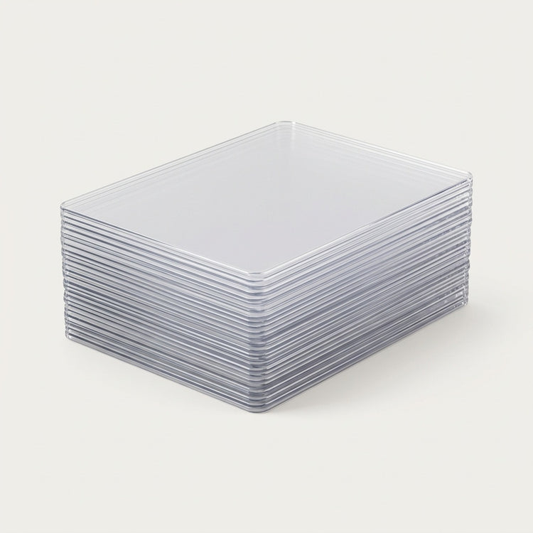 Clear plastic card sleeves are stacked neatly on a plain off-white background, showing their rigid edges and rounded corners.