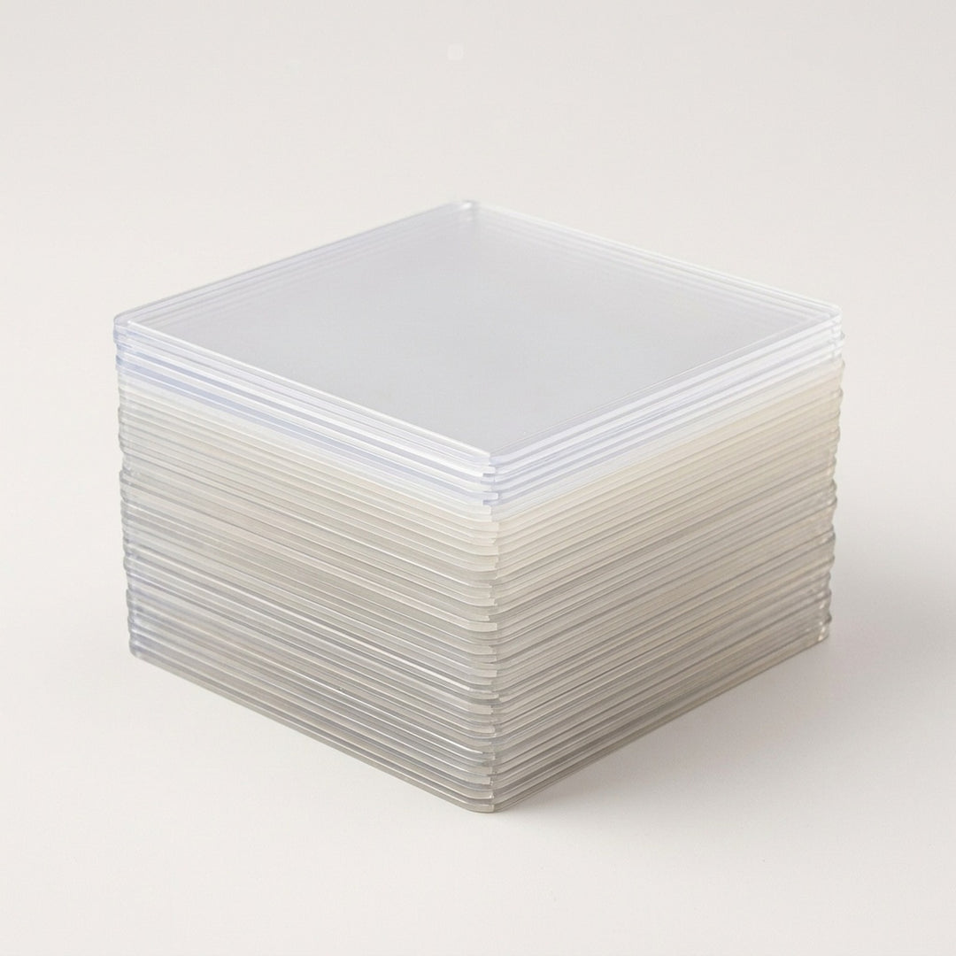 A stack of translucent hard card sleeves with rounded corners rests on a plain off-white background.