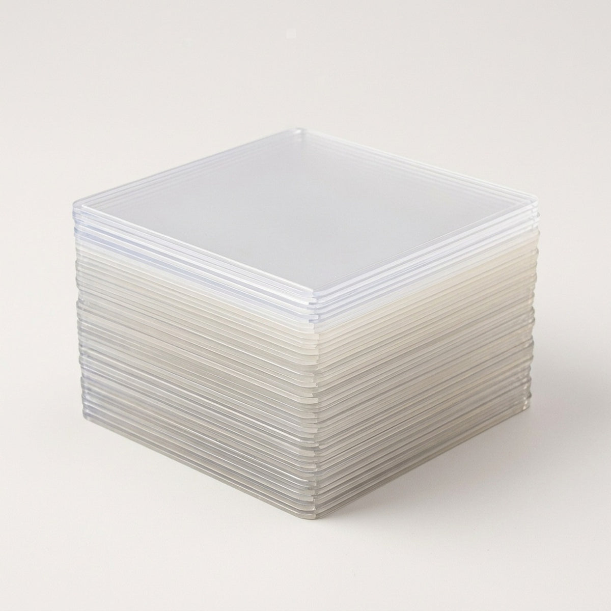 A stack of translucent hard card sleeves with rounded corners rests on a plain off-white background.