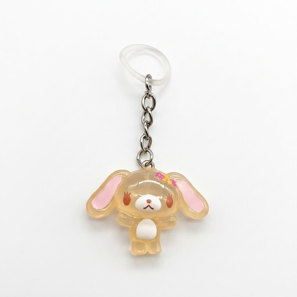 A Sanrio character keychain featuring a translucent, pale peach-colored bunny charm with pink inner ears, a small pink bow, and a white belly, attached to a silver chain and a clear plastic key ring on a white background.
