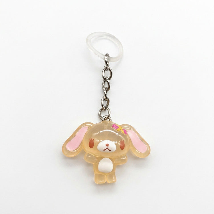 A Sanrio character keychain featuring a translucent, pale peach-colored bunny charm with pink inner ears, a small pink bow, and a white belly, attached to a silver chain and a clear plastic key ring on a white background.