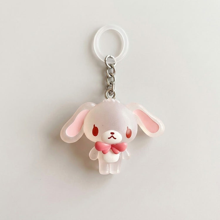 A cute translucent white bunny keychain charm with pink inner ears, red eyes, and a pink bow tie, attached to a silver chain and white key ring on a light gray background.