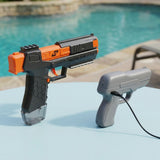 A black and orange water gun stands beside a smaller gray water gun with an attached black cable on a poolside table.