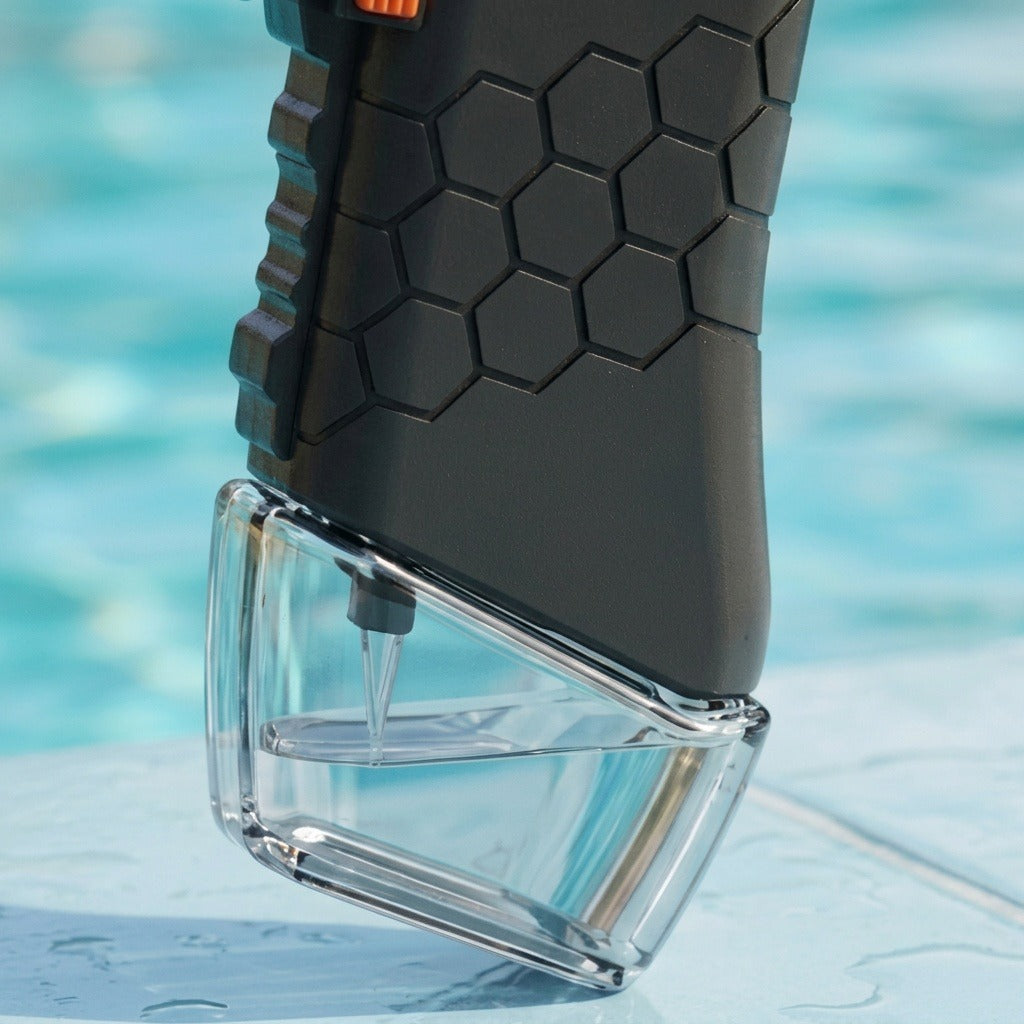 Water gun close-up shows a black hexagonal-textured grip and transparent reservoir partially filled with water against a blurred blue background.