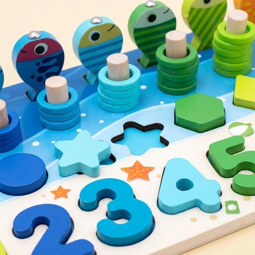Wooden activity board close-up showing blue and green fish, stacked counting rings, number pieces, and a loose turquoise star.
