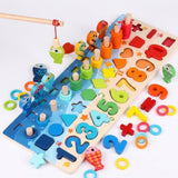 A rod lifts a green fish above a wooden activity board, with loose colorful rings, numbers, and shapes scattered around.