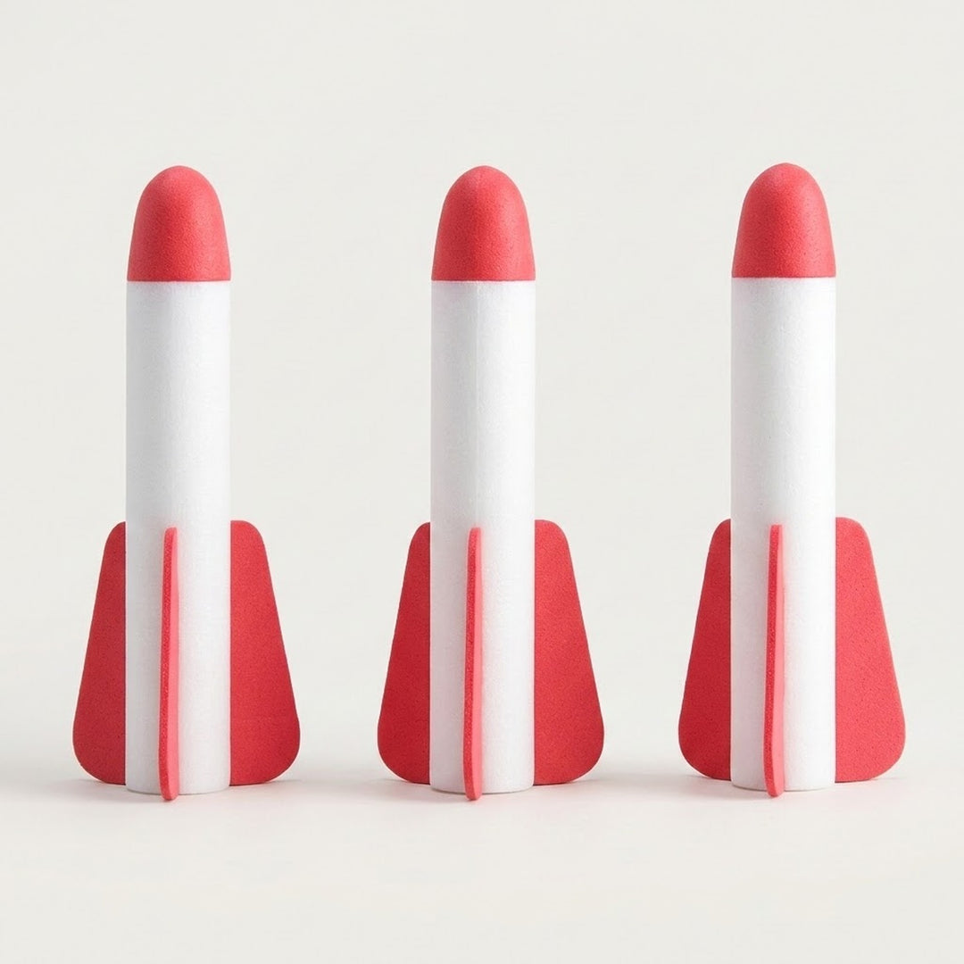 Three white EVA foam rockets with red tips and red fins from a rocket launcher toy standing side by side on an off-white background.