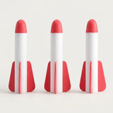 Three white EVA foam rockets with red tips and red fins from a rocket launcher toy standing side by side on an off-white background.