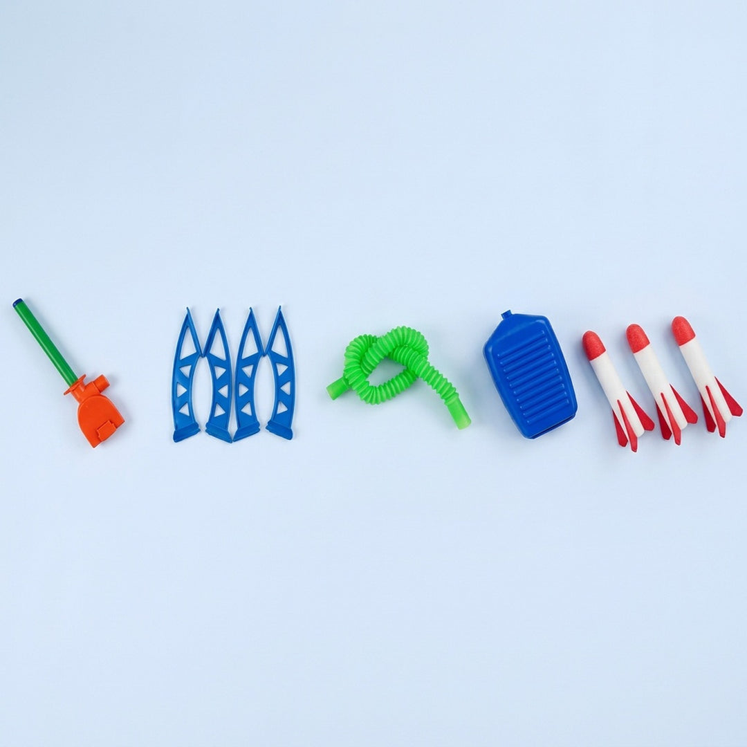 Disassembled launcher-and-3-rockets set of a rocket launcher toy laid out on a pale background, including blue legs, green hose, blue pump, and three red-and-white foam rockets.