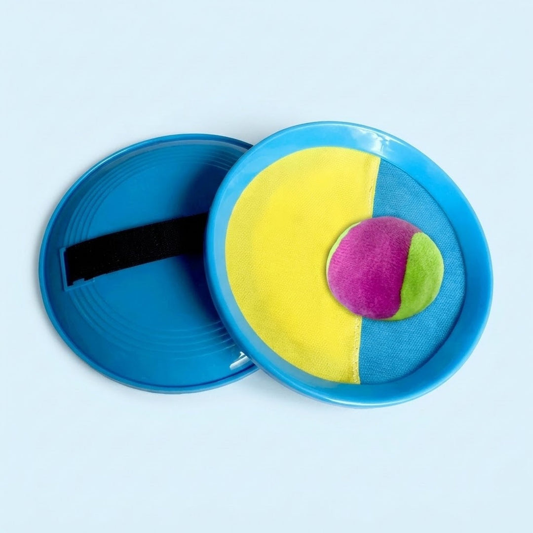 A catch game set with blue paddles, yellow-and-blue cloth faces, a black strap and a purple-and-green ball sits against a pale blue background.
