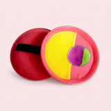 Catch game set with pink plastic paddles, yellow and pink cloth faces, a black hand strap, and a purple-green ball on pink.