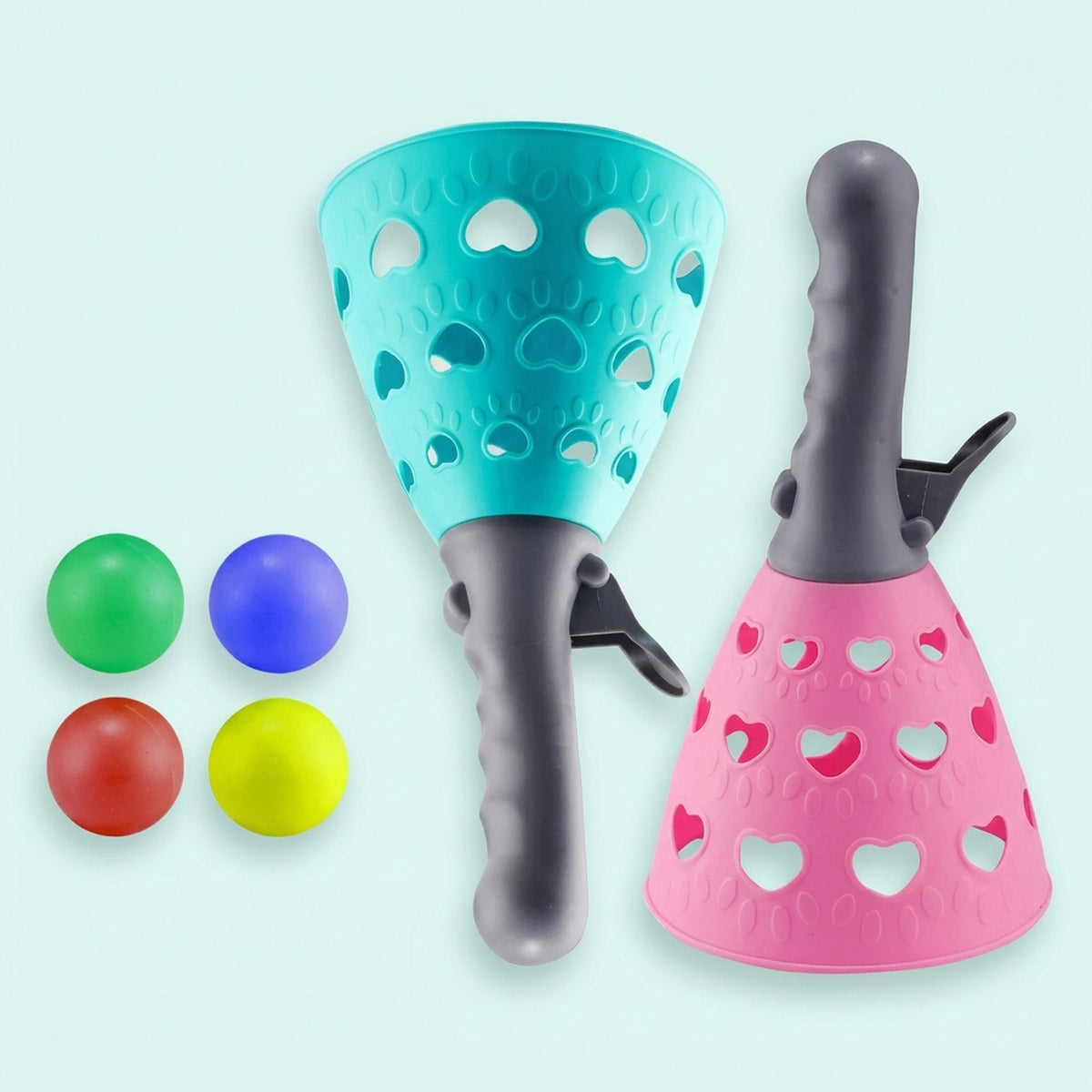 A catch game set with turquoise and pink perforated catchers, gray handles and four colorful balls sits against a pale mint background.