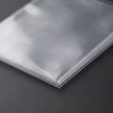 Clear plastic card sleeves sit stacked on a dark gray surface, with aligned corners and reflective edges shown close up.