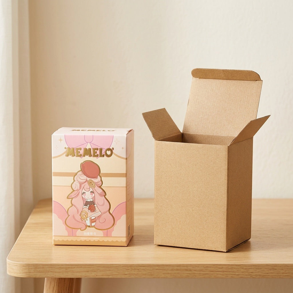Blind box figure packaging with pink and cream character artwork stands beside an open brown cardboard box on a wooden table.
