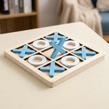 A wooden 3-player tic-tac-toe game board on a light wood table, with blue wooden X shapes and white O shapes visible.