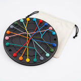 Black circular rope puzzle with crossing colorful ropes and a white drawstring bag behind it against a white background.