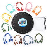 Rope puzzle components arranged on white, with a black circular board, colorful looped ropes, matching end pieces and a white drawstring bag.
