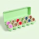 A light green plastic egg-shaped toy set arranged in a matching green carton on a pale mint background. The eggs are speckled off-white with colorful centers in purple, brown, red, green, blue, and tan.