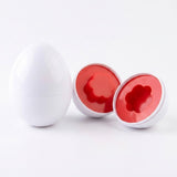 Matching egg set detail with one closed white egg beside two opened halves revealing red flower shapes on a white background.