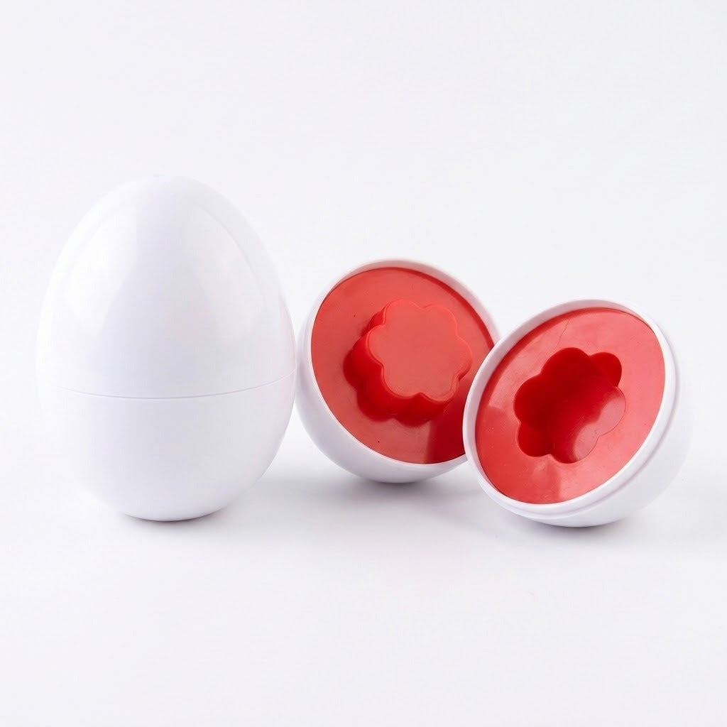 Matching egg set detail with one closed white egg beside two opened halves revealing red flower shapes on a white background.
