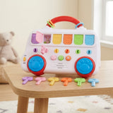 White pop-up toy with red carry handle and colorful flaps, one open showing a rabbit, six toy keys lined up on a wooden table.