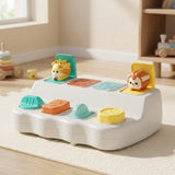 White pop-up toy with giraffe and lion raised sits on a cream rug in a sunlit nursery.