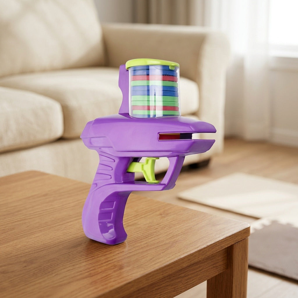 Purple plastic disc shooter with a green trigger and stacked colorful discs stands on a wooden table beside a cream sofa.