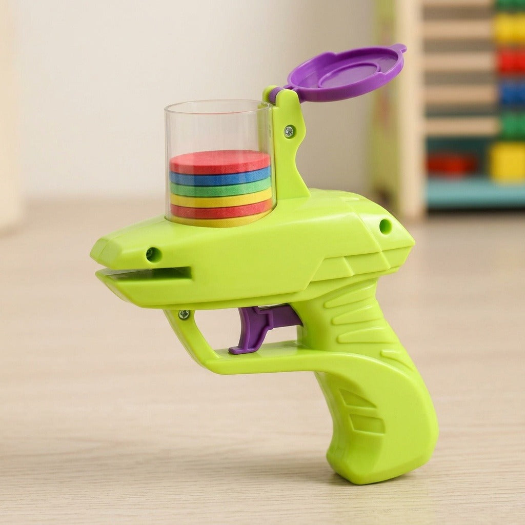 Lime green plastic disc shooter with a purple trigger and open purple lid holds colorful discs on a light wooden surface.