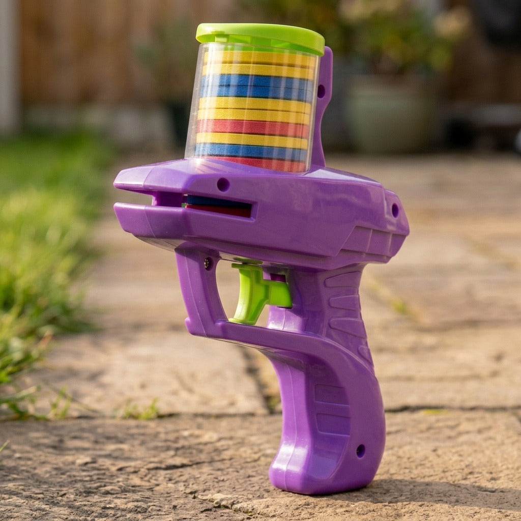 A purple plastic disc shooter with a green trigger and stacked colorful discs stands on a stone patio outdoors.