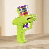 A lime green plastic disc shooter with a purple trigger and clear disc holder stands on wood against a cream background.