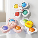 Rabbit, pig and duck suction spinner toys with colorful inserts are displayed against a smooth white surface beside a window.