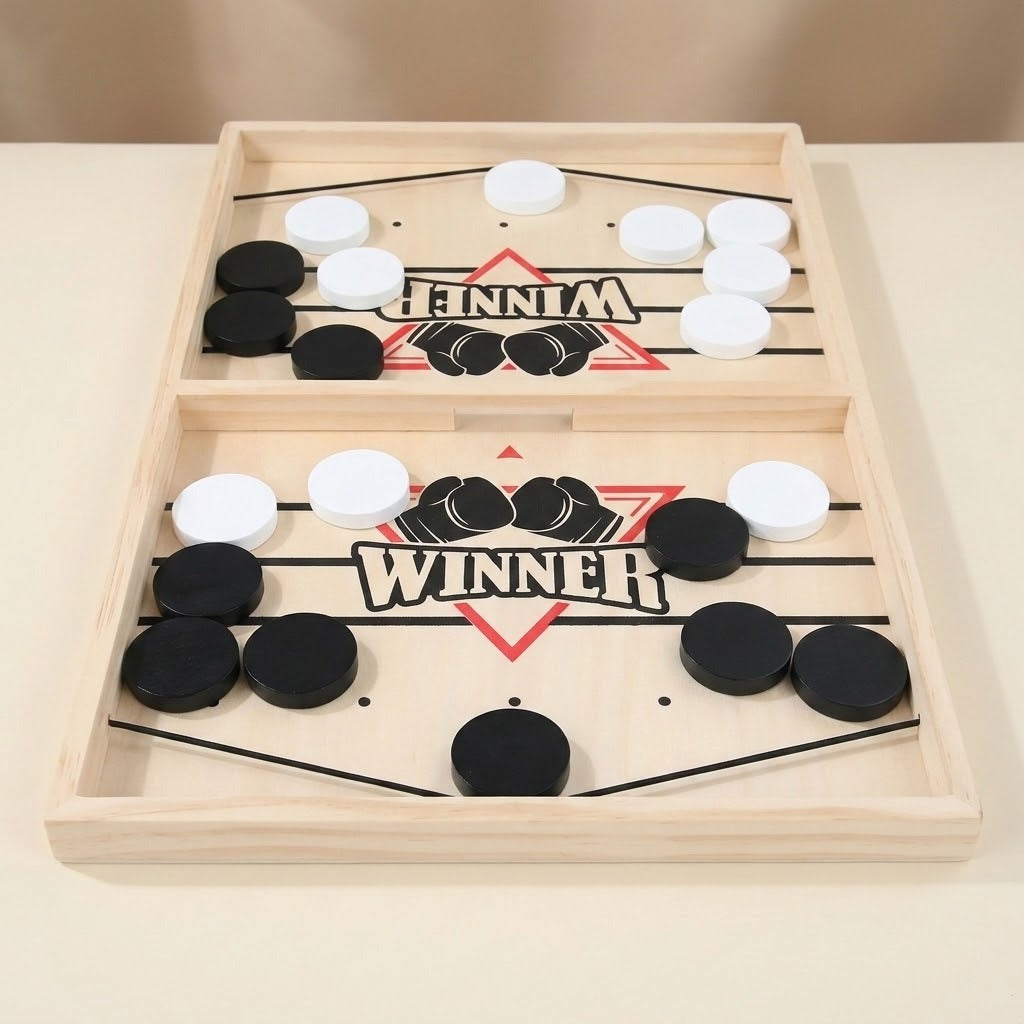 Light wood sling puck game with black and white pucks, elastic cords, and a central divider on a beige surface.