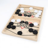 Wooden sling puck game with black and white pucks and black elastic cords, displayed diagonally against a white background.