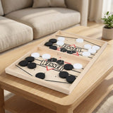 Light wooden sling puck game with black and white pucks on a wooden coffee table beside a beige sofa.