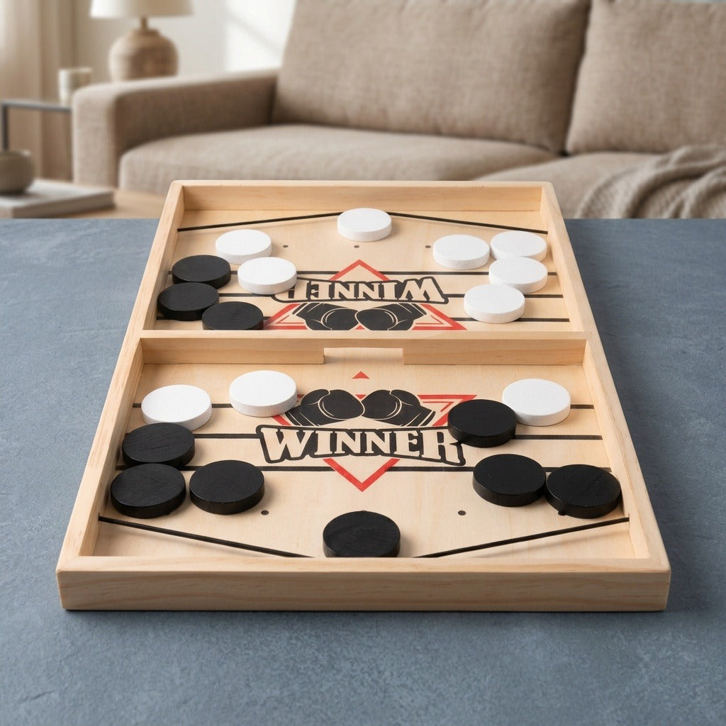 Wooden sling puck game with black and white pucks and a central opening on a gray tabletop before a beige sofa.
