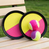 Catch game set with two pink-and-yellow discs with black rims and two multicolored balls on a wooden garden bench.