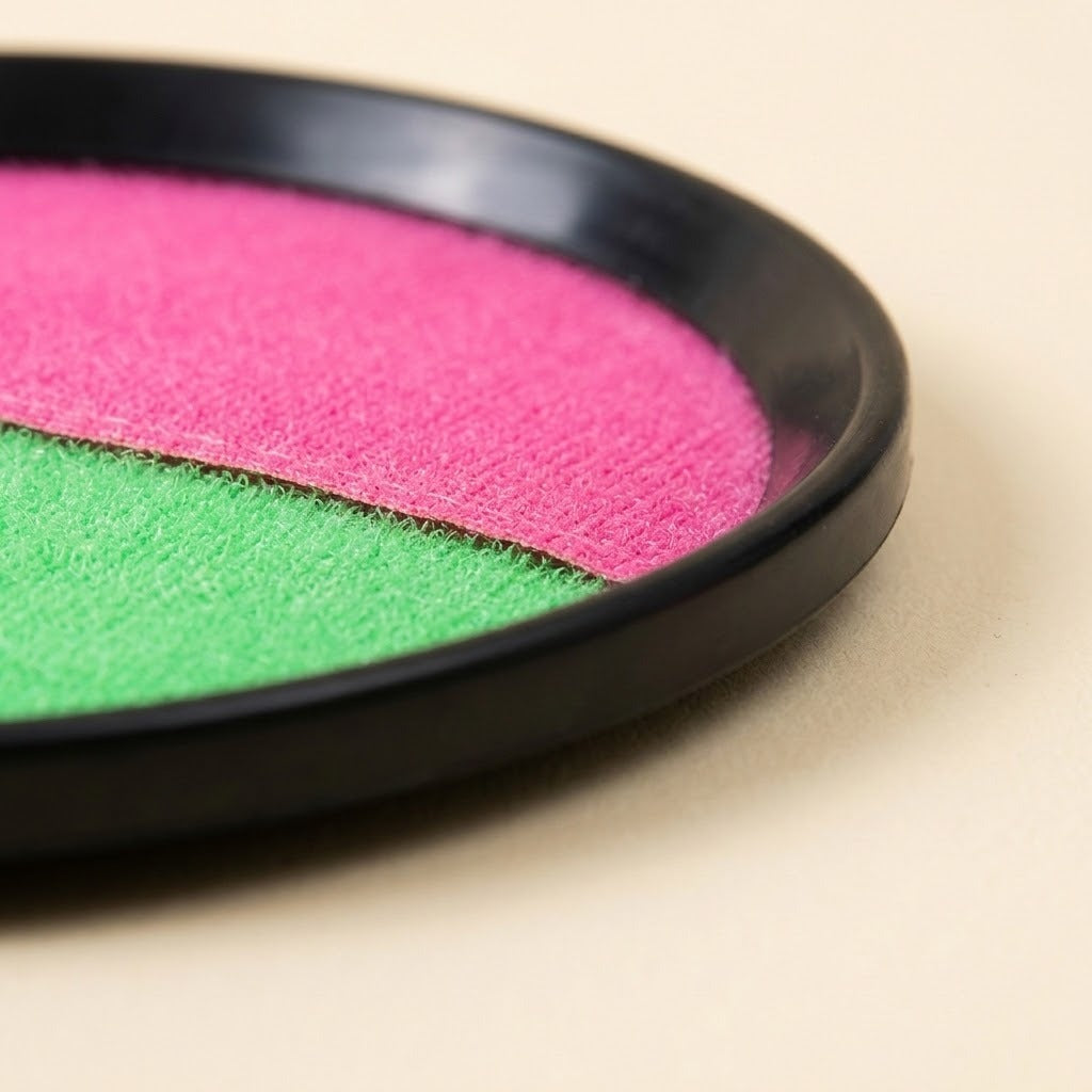 Catch game set disc close-up showing pink-and-green textured catching surfaces and a black plastic rim on a cream background.