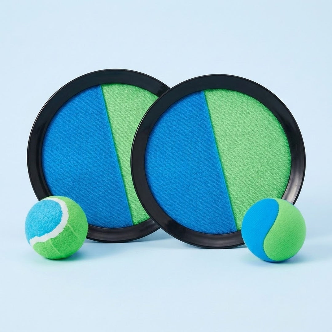Catch game set with two overlapping blue and green discs, black plastic rims, and two matching balls on a light blue background.