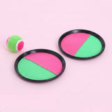 Catch game set with two pink and green discs, black plastic rims, and a matching ball on a light pink background.