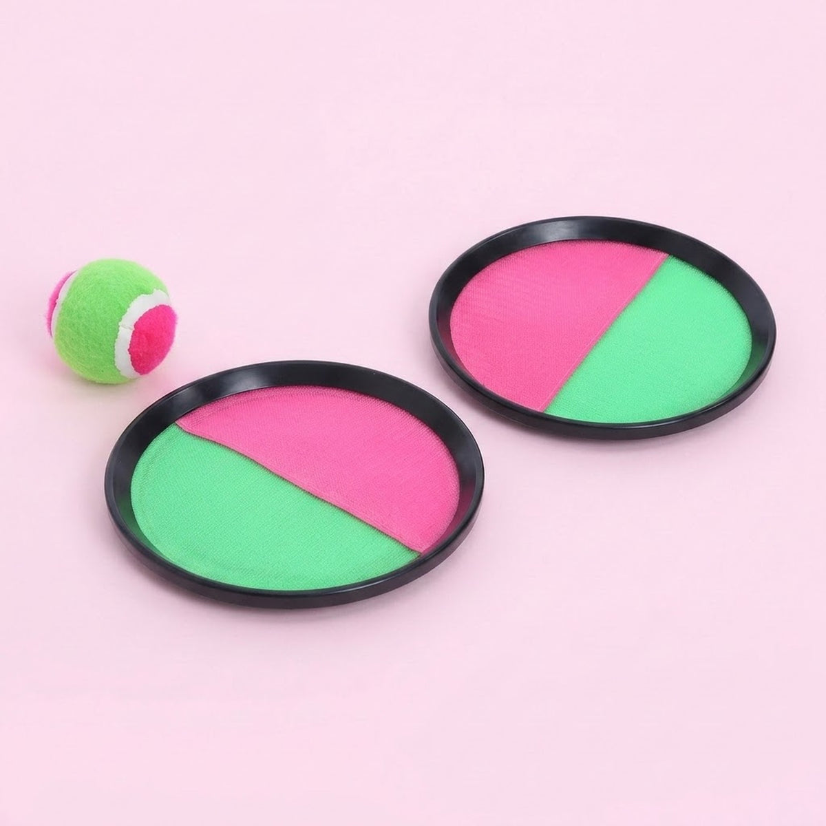 Catch game set with two pink and green discs, black plastic rims, and a matching ball on a light pink background.