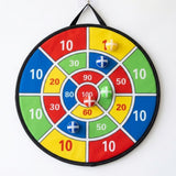 A colorful cloth dart board with numbered scoring sections hangs against a white wall with five sticky balls attached.