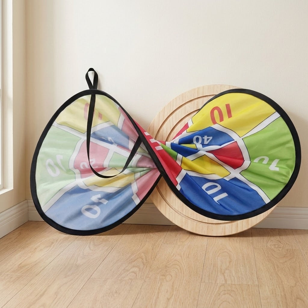 A colourful cloth dart board with black edging is twisted into two loops on a wooden floor beside a round wooden panel.