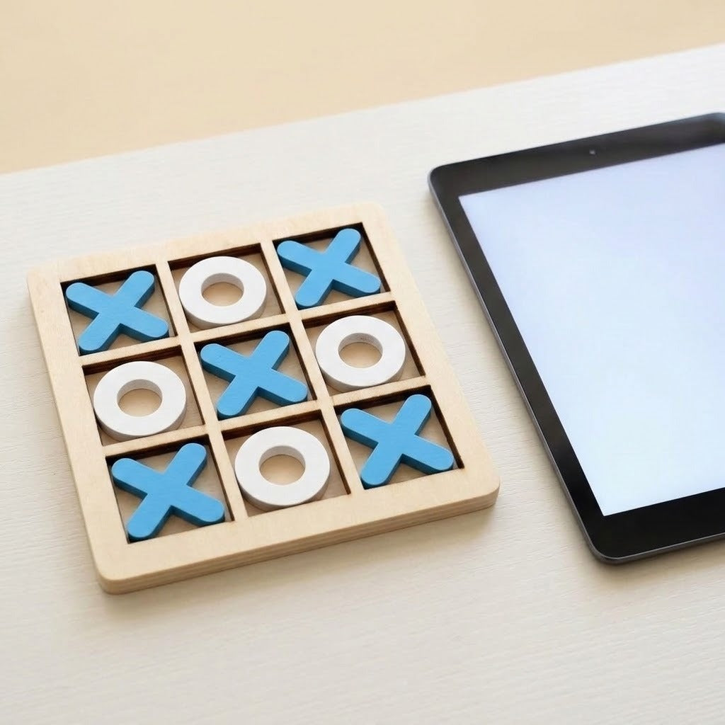 A wooden 9-square tic-tac-toe game board with blue X shapes and white O shapes, placed on a light tabletop next to a tablet.