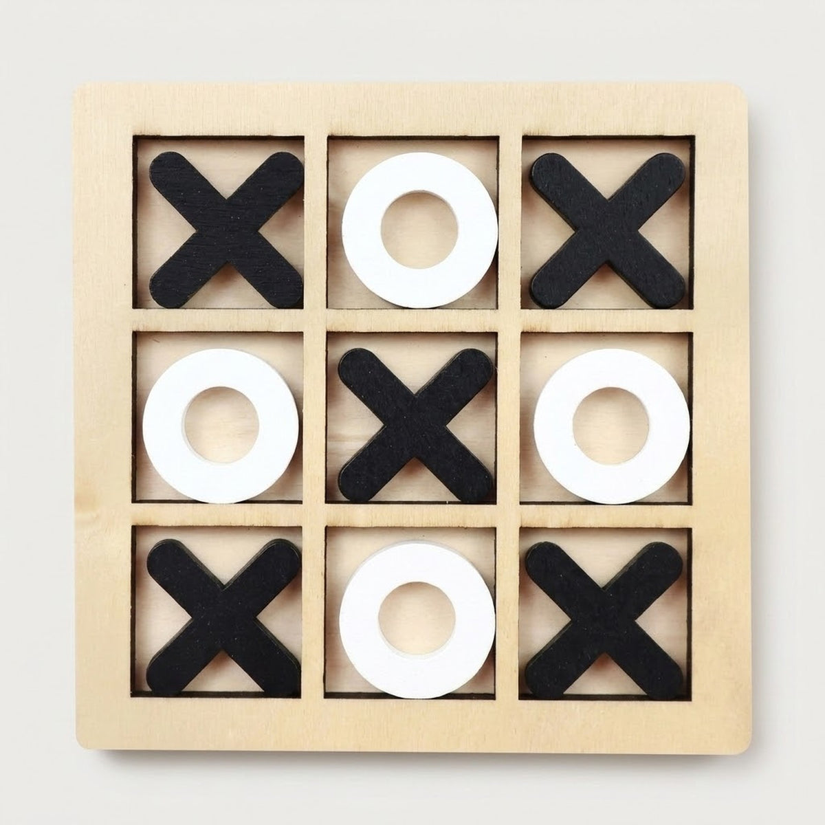 A wooden 3x3 tic-tac-toe game board with black X shapes and white O shapes arranged on a light natural wood frame, photographed from above on a plain light background.