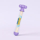 A plastic water gun toy with a clear cylindrical body, purple top and bottom caps, and a beige foam-like inner rod. The body has colorful printed graphics with the text 'water gun'.