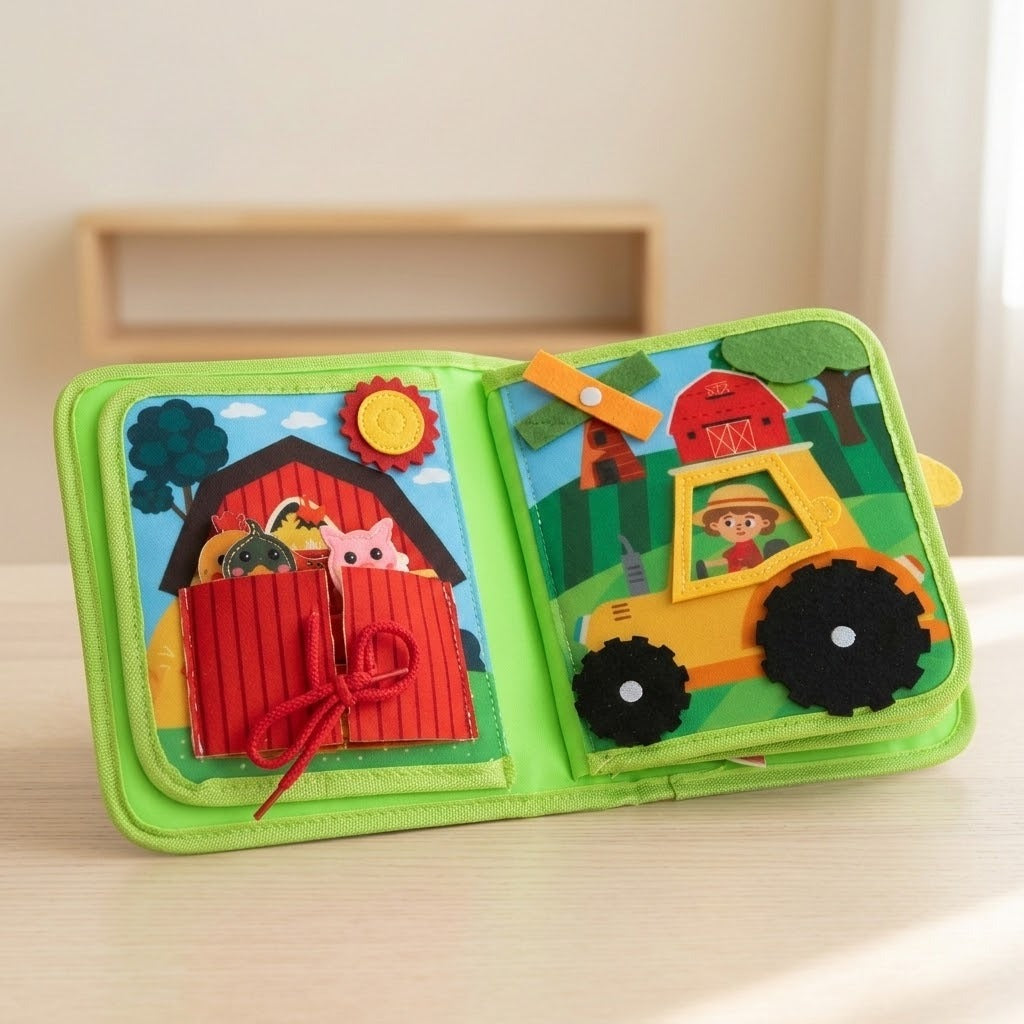 Green fabric busy book propped open on a light wooden surface, showing a red barn pocket and yellow tractor activity.